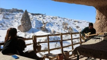Kapadokya'da tuğra eklenmiş olan turistler 'gitarlı rehber'in nağmeleriyle eğleniyor